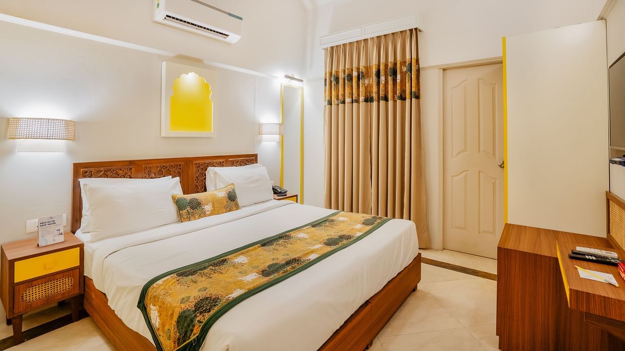 An image of a king size bed in a bedroom that has a fan, AC, bedside table, and ceiling light  - Shri Radha Brij Vasundhara Resort & Spa, Mathura