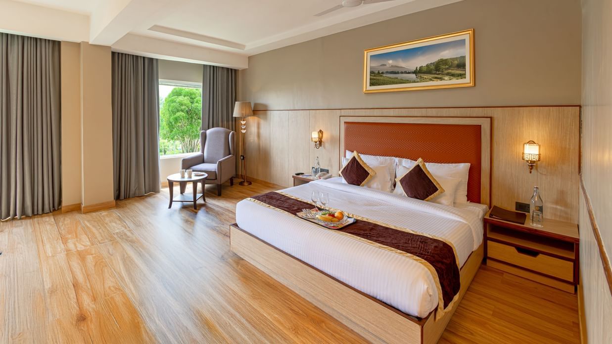 Elegant room at The Lalita Grand Mathura - Vrindavan with a king size bed, wooden flooring, large window views, and refined contemporary decor.