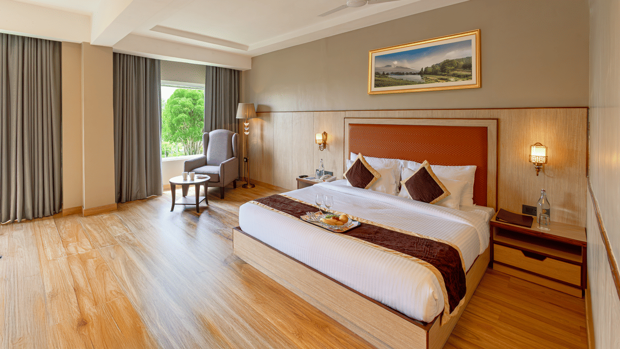 Elegant room at The Lalita Grand Mathura - Vrindavan with a king size bed, wooden flooring, large window views, and refined contemporary decor.