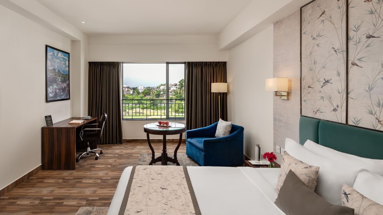 Guest room at Voyage Milestone Hotel and Banquet with a writing desk and window view.