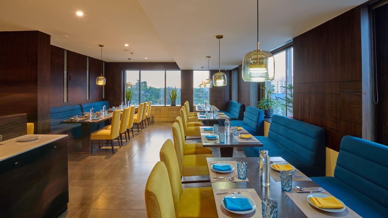 Restaurant at Voyage Milestone Hotel and Banquet with yellow chairs and blue cushioned seating.