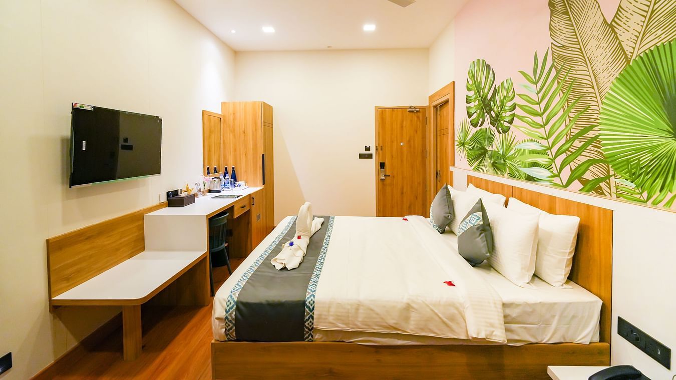Image of bedroom featuring a plush bed in front of a wall decorated with wallpaper and a TV in the front