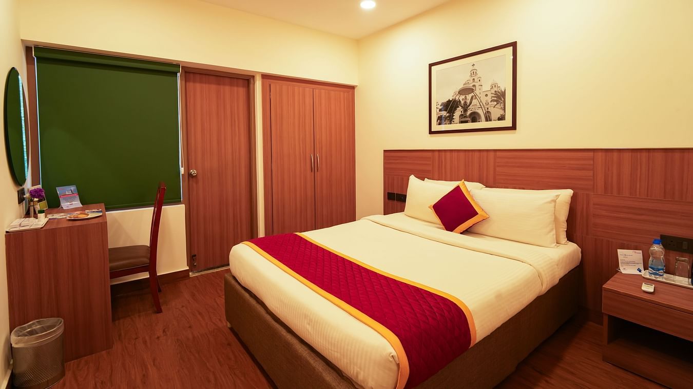 Bedroom in warm lighting featuring a double bed and a framed painting over it and a nightstand next to it