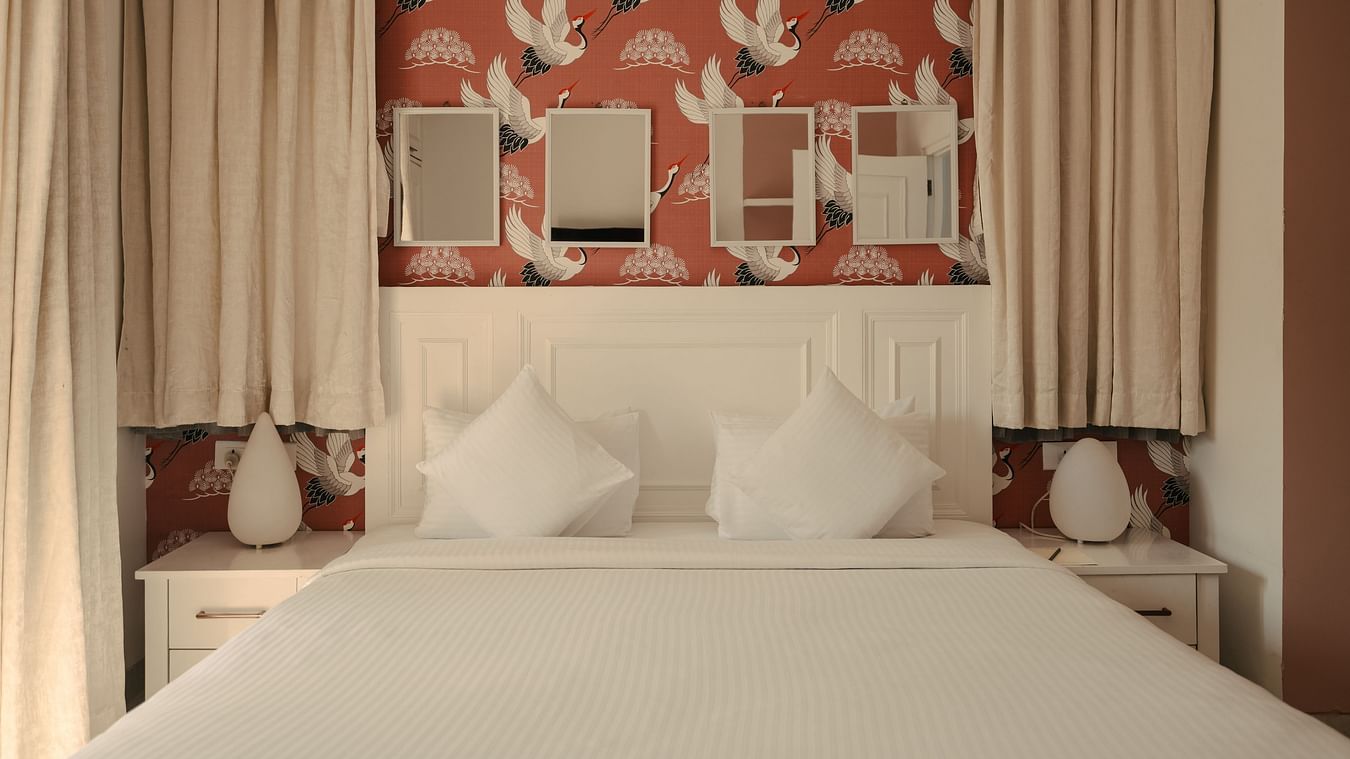 Elegant bedroom with red accent wallpaper and twin mirrors at Three BHK Premium Villa, Richmonde Ananta Elite, Goa.