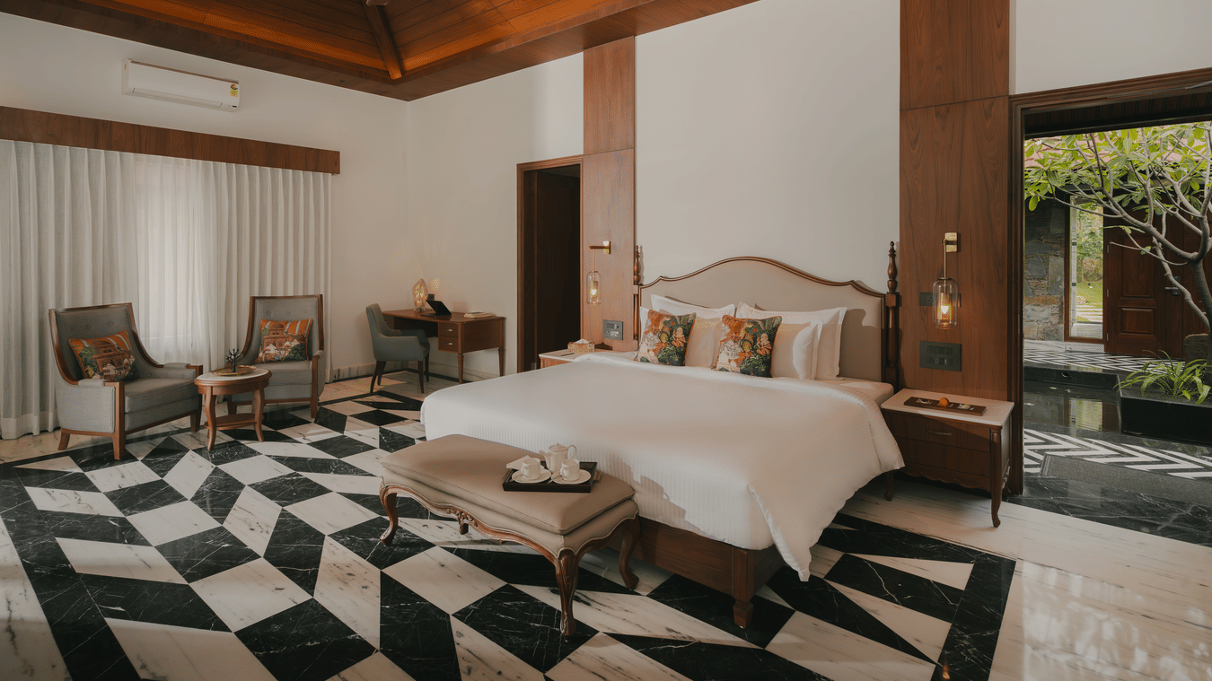 Spacious bedroom with tiled floor and sitting area at The Ananta Udaipur.