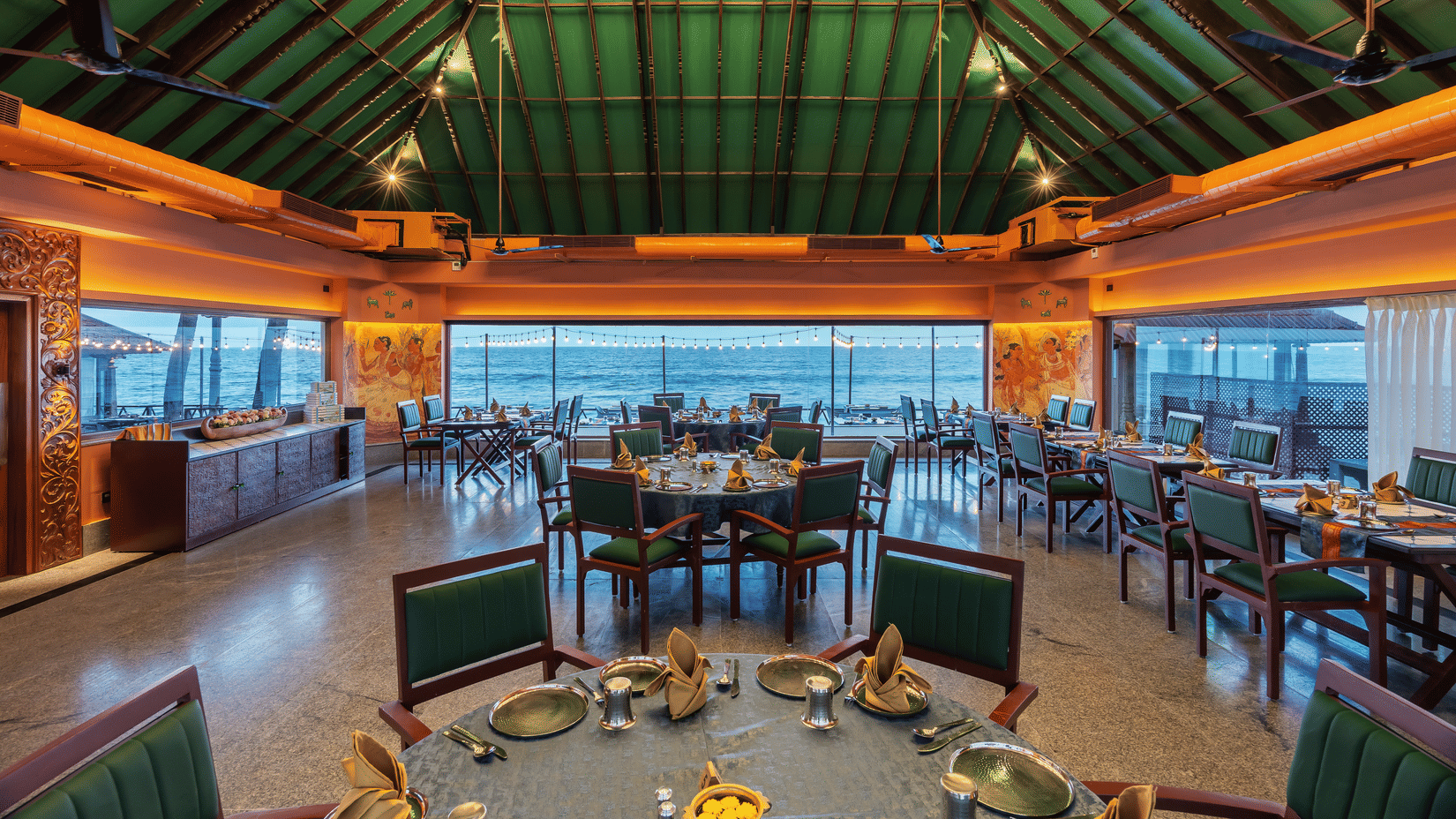 Spacious restaurant interior at MGM Beach Resorts with a green-tinted glass roof and panoramic beach side windows.