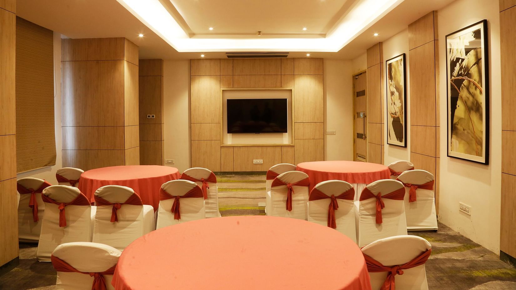 A conference hall in Zirakpur with the chairs turned towards a wall with a mounted television - Tulip Inn, Zirakpur