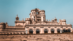 Facade of a grand heritage palace under a bright blue sky.