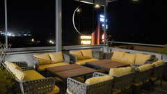 The open-air rooftop dining area at Pride Elite Himmatnagar looks vibrant under cozy nighttime illumination.