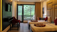 A modern hotel room with two twin beds featuring padded beige headboards and decorative throws