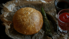 A plate of Kachori kept on a paper with a chilly and tomato sauce and mint chutney next to it