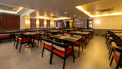A wide-angled view of the clean dining hall at VITS Select, Bengaluru, with rows of tables, chairs, and soft cove lighting - one of the best restaurants in Hebbal.