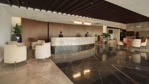 View of the main reception desk in the hotel lobby with staff and polished dark floors at Arawali Ananta Elite, Jaipur.