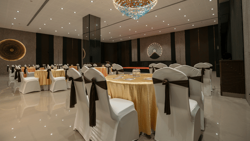 An event space with round tables draped in white, set for a formal function - Biznotel By Pride Surat