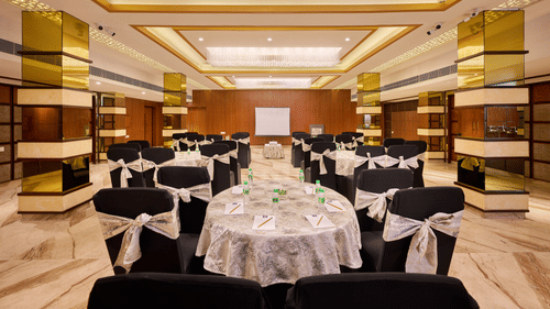 An image of the royal hall with round tables, ambient lighting and a wall mounted screen in front