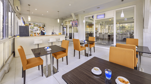 Modern dining space inside the Golden Tulip, Candolim, Goa, with light-coloured furniture and natural lighting.