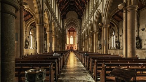 interior view of a cathedral with benches and an altar in view in the distance