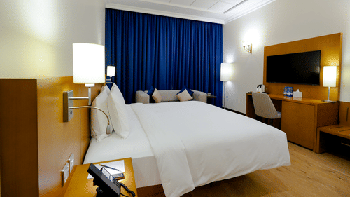 A double bed with side tables and lamps inside Classic Premium King - La Maison Hotel, Doha
