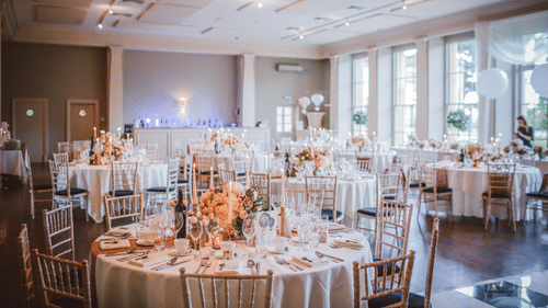 round table seating arrangements inside a banquet hall with cutlery on the table
