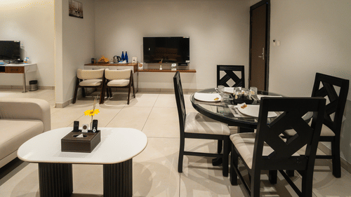 An image of the hotel room with a dining table, a sofa, and a wall-mounted television - MGM Whispering Meadows