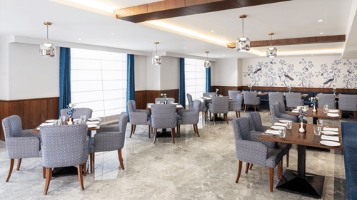 An image of our restaurant in Haridwar featuring comfortable upholstered chairs around tables, creating a warm ambience for your dining experience - MJ Sarovar Portico, Haridwar
