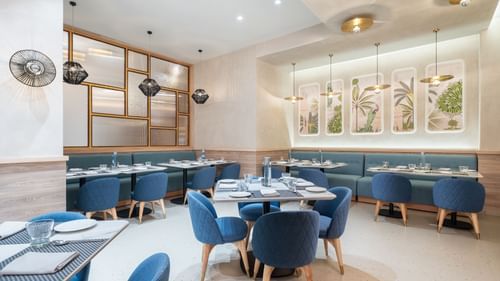 A dining area with a marble floor and blue upholstered chairs.