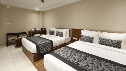 Superior Twin Room at Pride Biznotel Canopus, Digha featuring two double beds placed next to each other and a sitting space in the background featuring a two-seater sofa and a coffee table next to the work desk