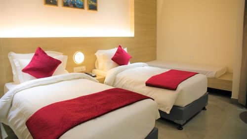 Deluxe Twin Bedroom at Pride Biznotel Haldwani featuring a couple of twin beds with a common headboard with warm lighting