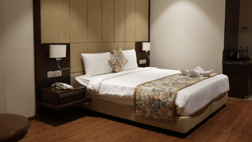 Standard Room at Pride Hotel Bhopal featuring a double bed with two nightstands attached to the large headboard and lamps on both sides