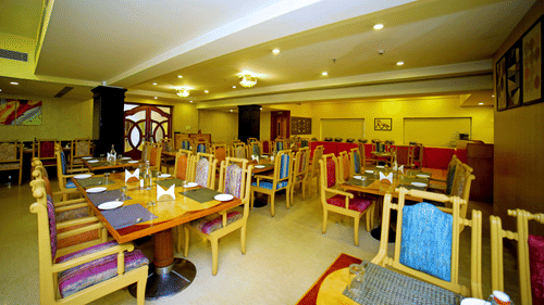 Indoor dining area with wooden tables and chairs at Raj Park Hotel, Tirupati.