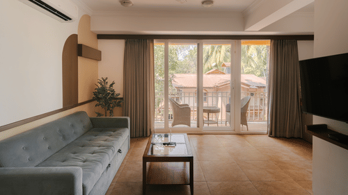 Well-lit living room with a cozy seating area and a balcony at the Two BHK apartment in Richmonde Ananta Elite, Goa.