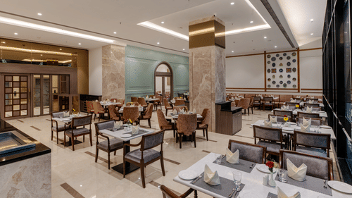 A stylish dining area in a restaurant in Ajmer featuring elegant decor, plush seating, and a relaxed ambience - Sarovar Portico, Ajmer