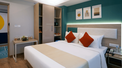 a double bed beside the wardrobe and tables in one of the standard rooms at Sarovar Portico, Kolkata Rajarhat