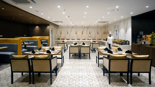 a chef standing inside Golpo all-day dining at Sarovar Portico, Kolkata Rajarhat 