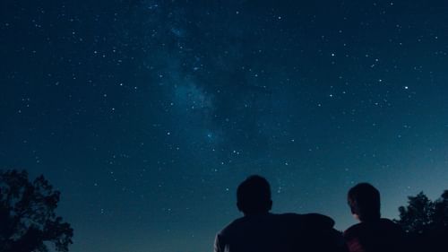 People gazing up at the night sky filled with stars