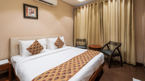Cosy guest room with double bed, soft lighting, neutral décor, and curtains for a relaxing stay experience.