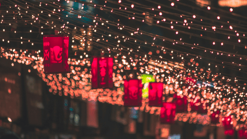 An image of beautiful decoration above a street with fairy lights and red coloured paper lanterns.