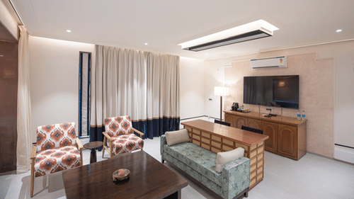 A TV screen and comfortable chairs in a bedroom corner at The Sierra