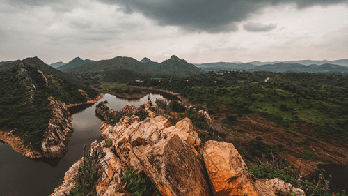 Nature with a small steam running on the left and greenery and hills in the background