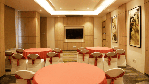 A conference hall in Zirakpur with the chairs turned towards a wall with a mounted television - Tulip Inn, Zirakpur