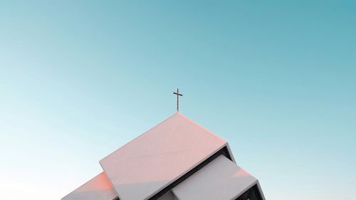 White church with cross against blue sky.