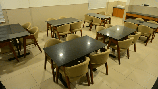 Casual dining area at Bhavanis Vista By Icon Hosur with neatly arranged tables and chairs in a well-lit space.