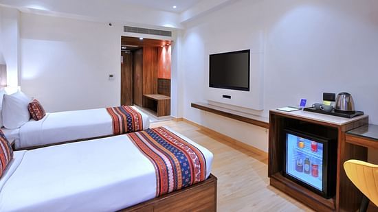An image of twin bed, a minibar and a television in our room in Agra - Golden Tulip, Agra