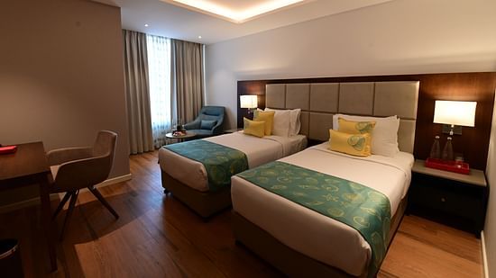 A room at Golden Tulip Vagator, Goa with twin beds and a work desk and chair