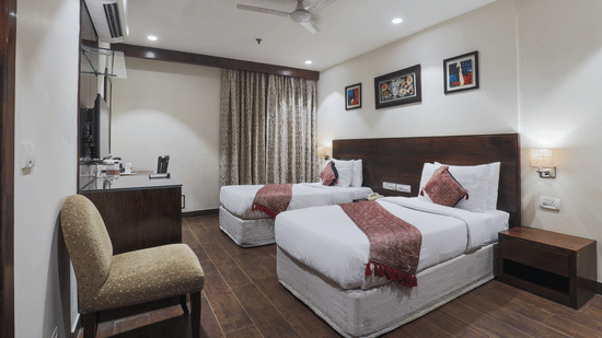 Twin room with wood flooring, red accent throws, and framed wall art at Hotel Bluestone (Nehru Place) by The Cosy Hotels