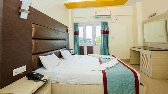 A double bed with side tables, a cushioned headboard and mirror opposite in Sea View - Hotel Shompen