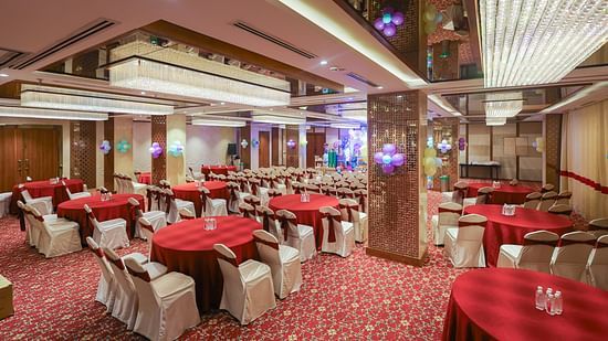 Side view of Blossom hall with stylish decor, lights, and round seating at Icon Premier Hotel by Bhagini, Devarabisanahalli