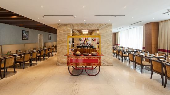 Restaurant with a chaat section on a small wheel and seating arrangements in the corner at Icon Premier Hotel by Bhagini, Devarabisanahalli