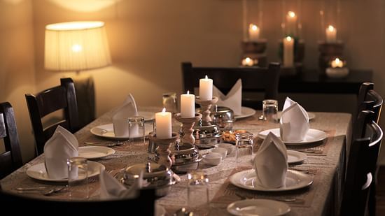 An image of a dining table set with candles and there are chairs spread on all sides at Lamrin Boutique Cottages, Rishikesh