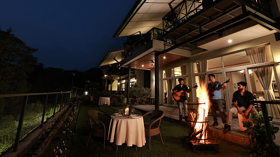 An image of three men singing and playing guitars near bonfire at Lamrin Norwood Green, Palampur